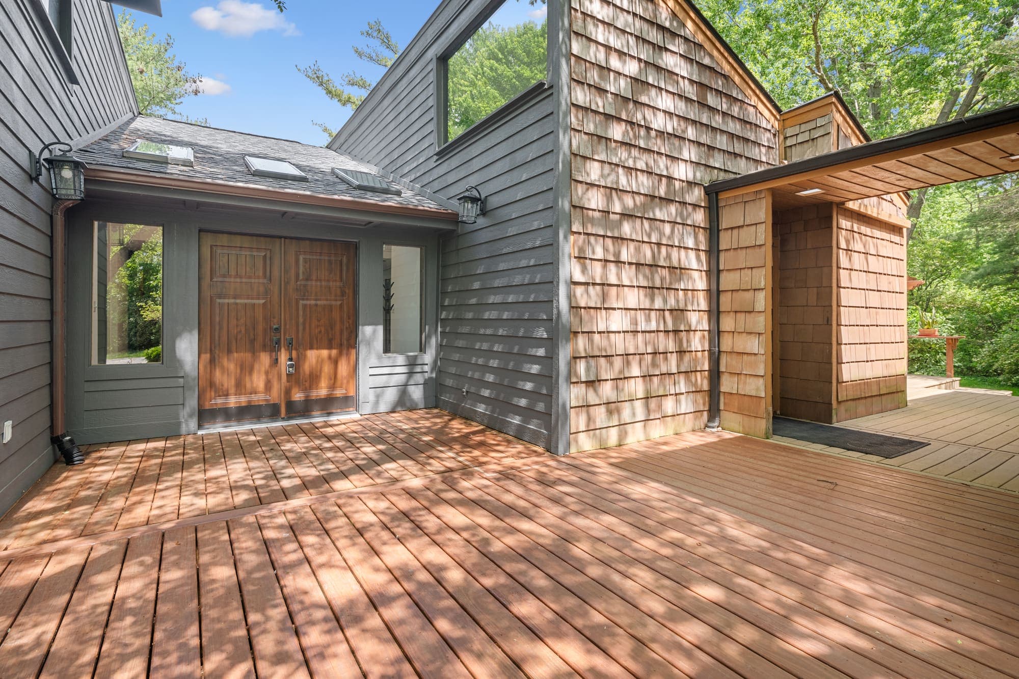 Cedar home exterior with wraparound deck under mature trees