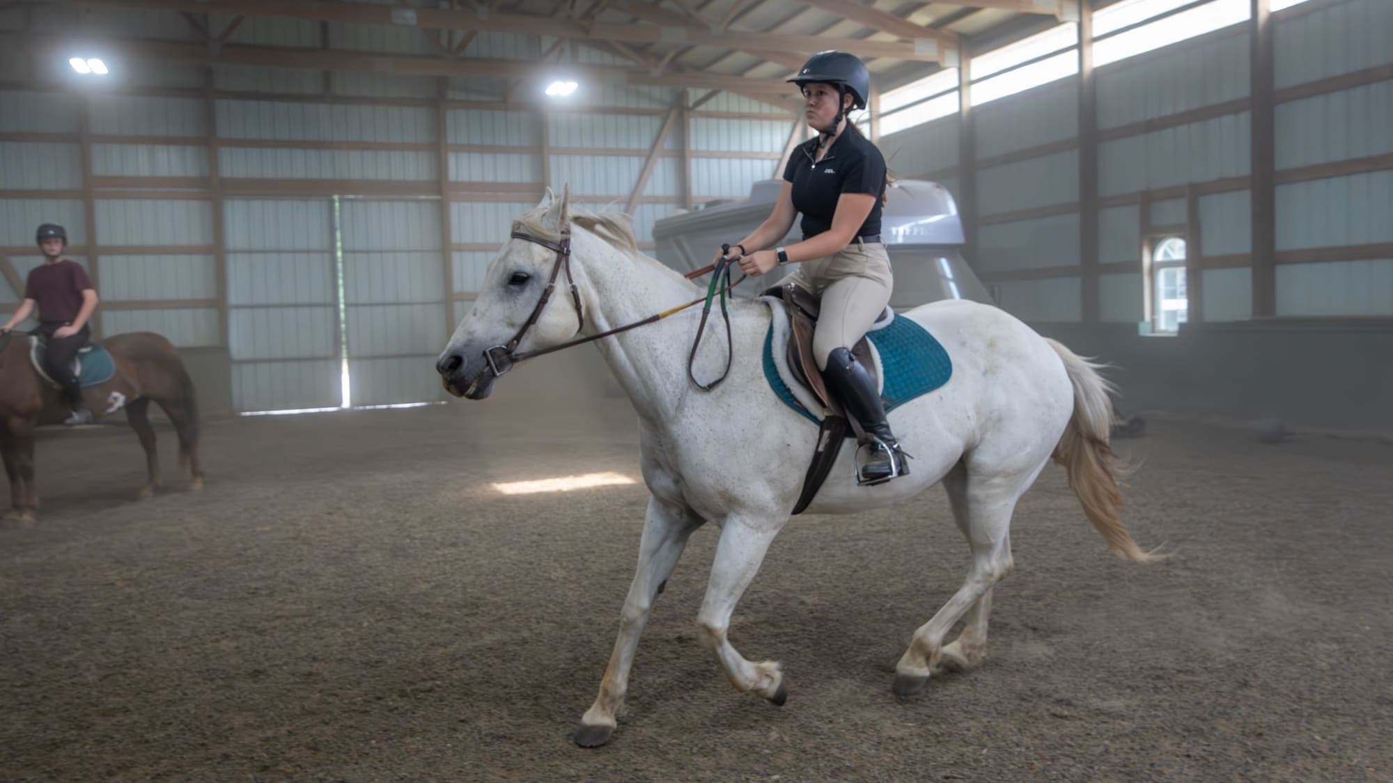 Rider on a gray horse inside a private riding arena