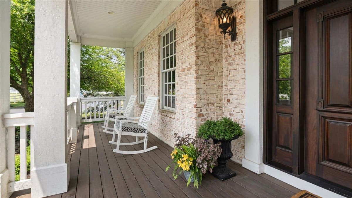Covered front porch with brick arches, rocking chairs, and hanging lanterns