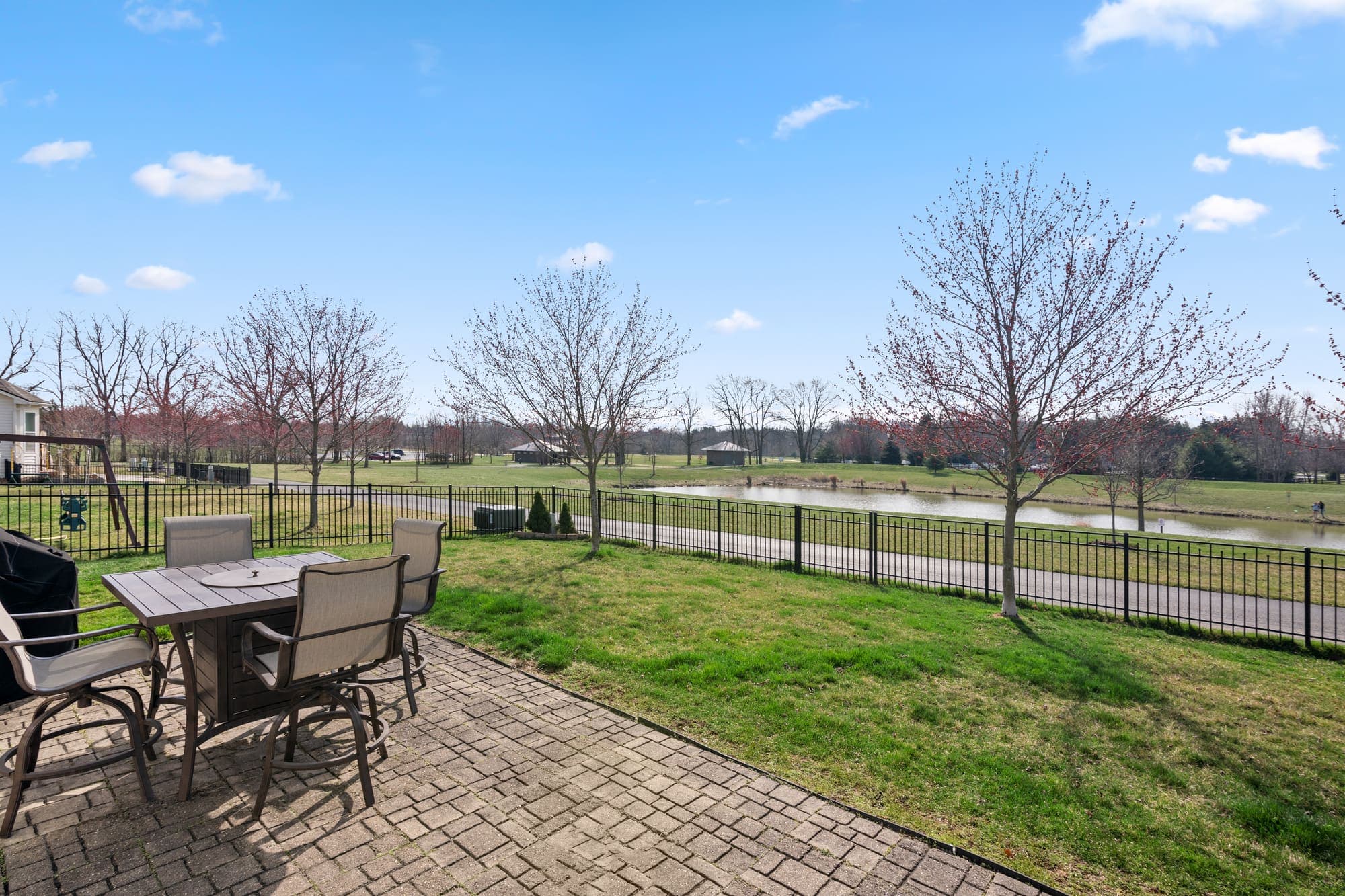 Stamped concrete patio overlooking a fenced yard and pond