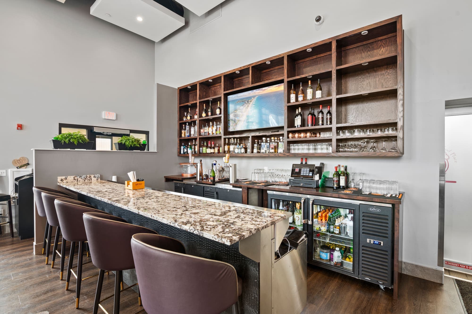 Bar with stone counter, wood shelving, and pendant lights